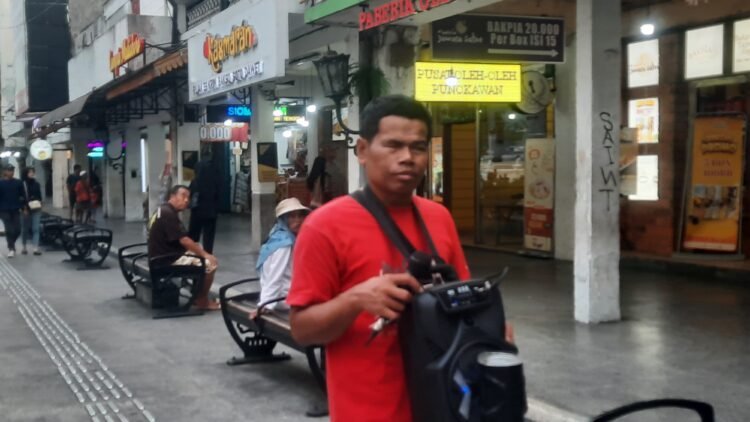 Pengamen tunanetra Mujiono saat mengamen di kawasan pedestrian Malioboro, Kamis (9/10/2025).