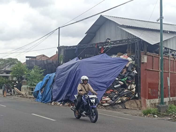 Pengendara motor melintas di depan sampah yang menumpuk di depo kawasan Lempuyangan, Kota Yogyakarta.