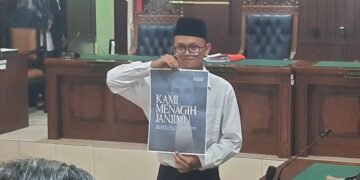 Terdakwa kasus pembakaran tenda polisi di Mapolda DIY saat mempelihatkan poster di ruang persidangan menagih janji ketua Majelis Hakim Ari Prabawa sebelum mengikuti sidang vonis, Senin (23/2/2026).