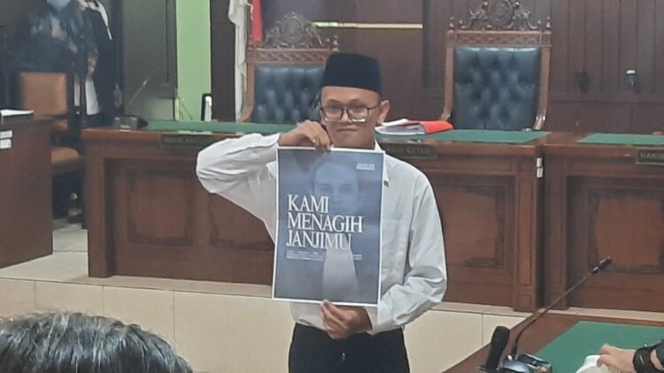 Terdakwa kasus pembakaran tenda polisi di Mapolda DIY saat mempelihatkan poster di ruang persidangan menagih janji ketua Majelis Hakim Ari Prabawa sebelum mengikuti sidang vonis, Senin (23/2/2026).