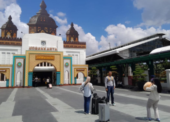 Sejumlah pemudik tampak meluangkan waktu untuk berfoto di depan fasad Stasiun Tugu Yogyakarta yang dihiasi ornamen bernuansa Ramadan, pada Senin (16/3/2025).