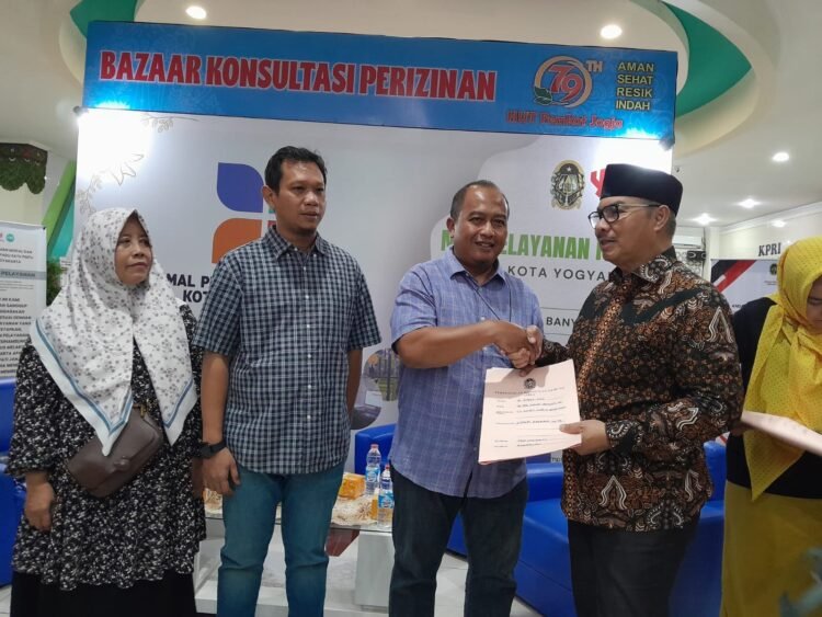 Wali Kota Yogyakarta, Hasto Wardoyo (kanan), menyerahkan berkas PBG kepada warga saat kegiatan Bazar Perizinan dan Unit Reaksi Cepat Konsultasi PBG di Mall Pelayanan Publik (MPP) kompleks Balai Kota Yogyakarta, pada Selasa (2/6/2026).