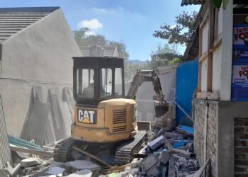 Satu unit alat berat ekscavator dikerahkan untuk membongkar bangunan liar di atas saluran irigasi di Padukuhan Sedan, Kalurahan Sariharjo, Kapanewon Ngaglik, Kabupaten Sleman, DIY, Rabu (1/7/2026).